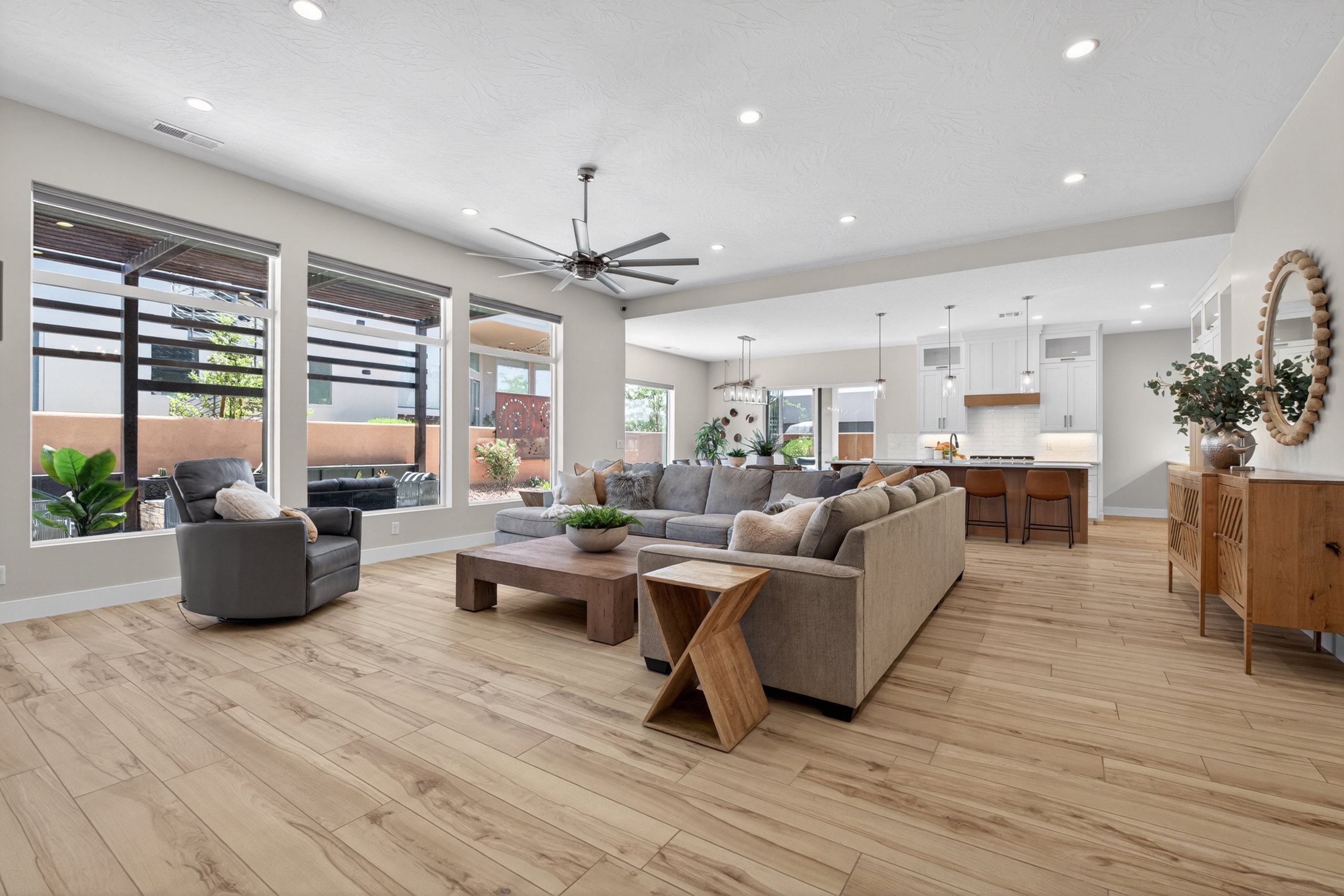 Open-concept living great room featuring motorized blinds for privacy, wood-finish flooring, recessed lighting, and a contemporary ceiling fan.