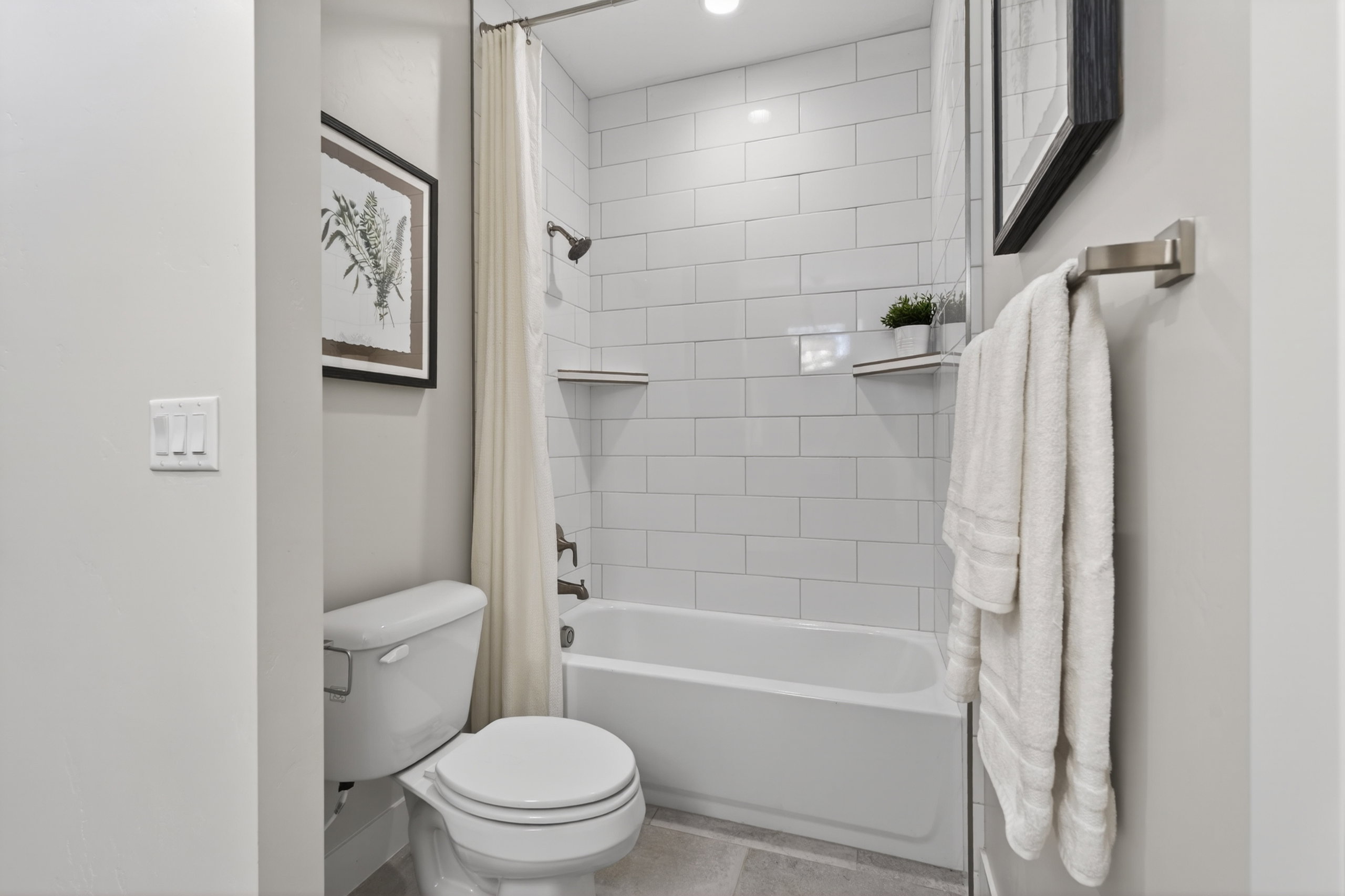 Bathroom featuring a white subway tile shower surround with integrated shelving, a built-in bathtub, and dark bronze bath fixtures