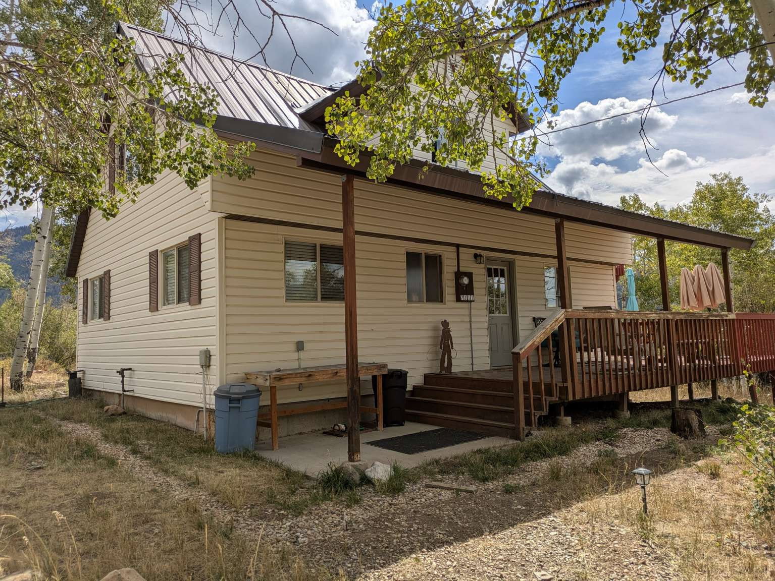 Exterior featuring a covered porch, wood-finish decking, and light-colored siding