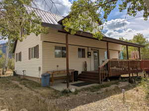 Exterior featuring a covered porch, wood-finish decking, and light-colored siding