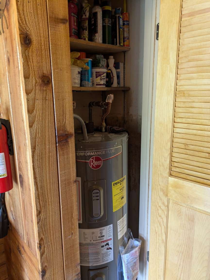 Utility closet featuring a water heater and integrated shelving