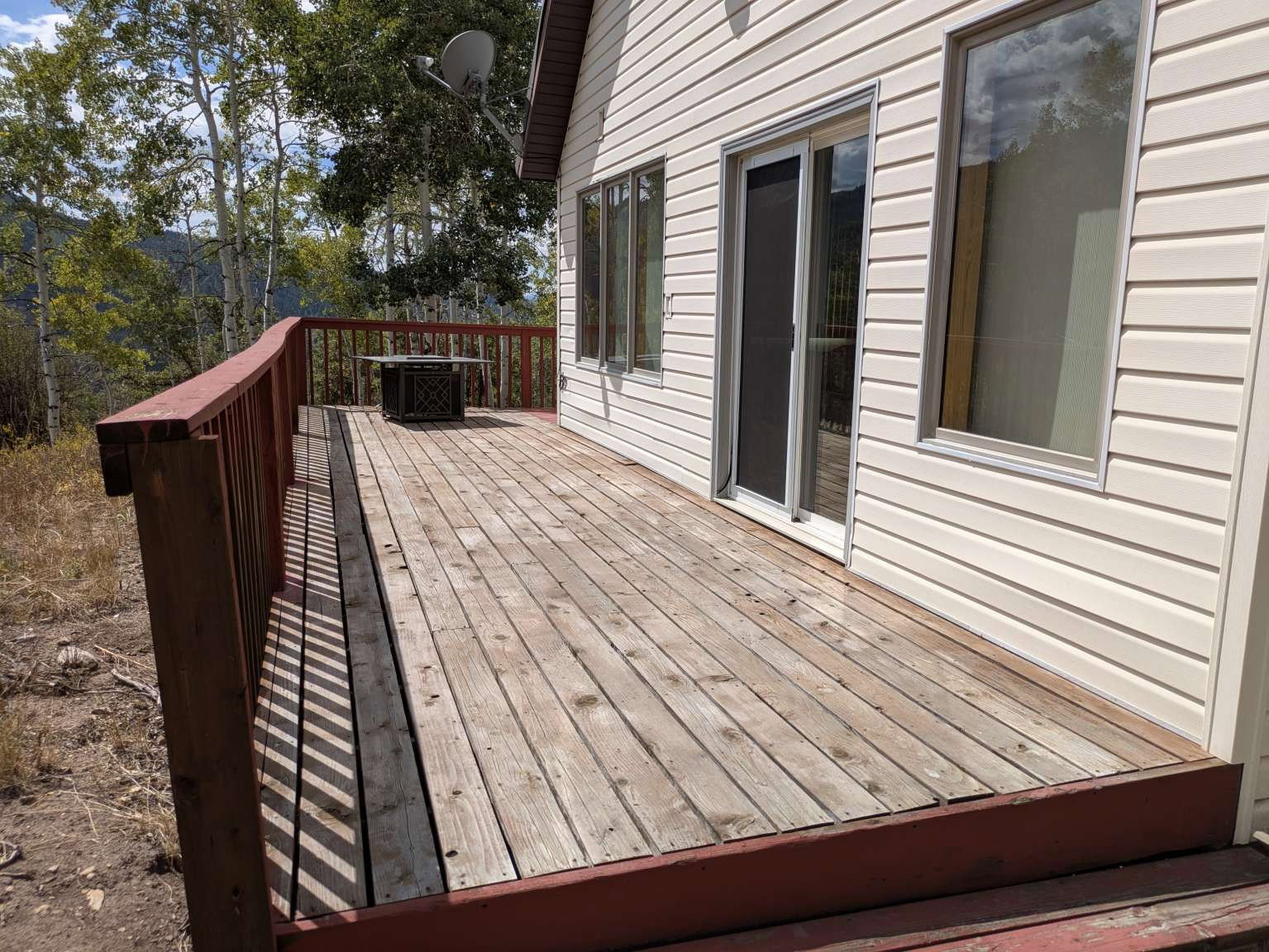 Expansive wood deck with a red painted railing, offering direct access to the interior via a sliding glass door