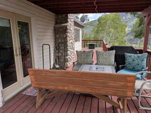 Expansive red-stained deck featuring a stone-clad exterior wall and glass-paneled double doors