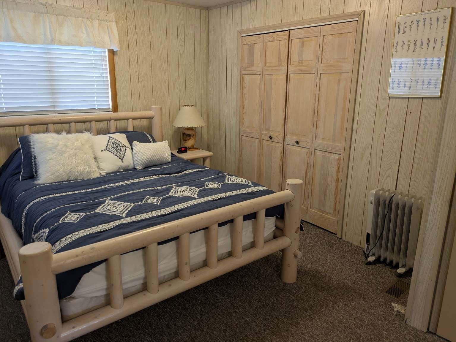 Wood-paneled interior walls, window with blinds, bi-fold closet doors, and carpet flooring