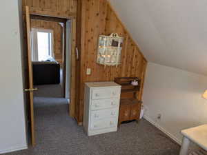 Sloped ceiling room featuring wood paneling