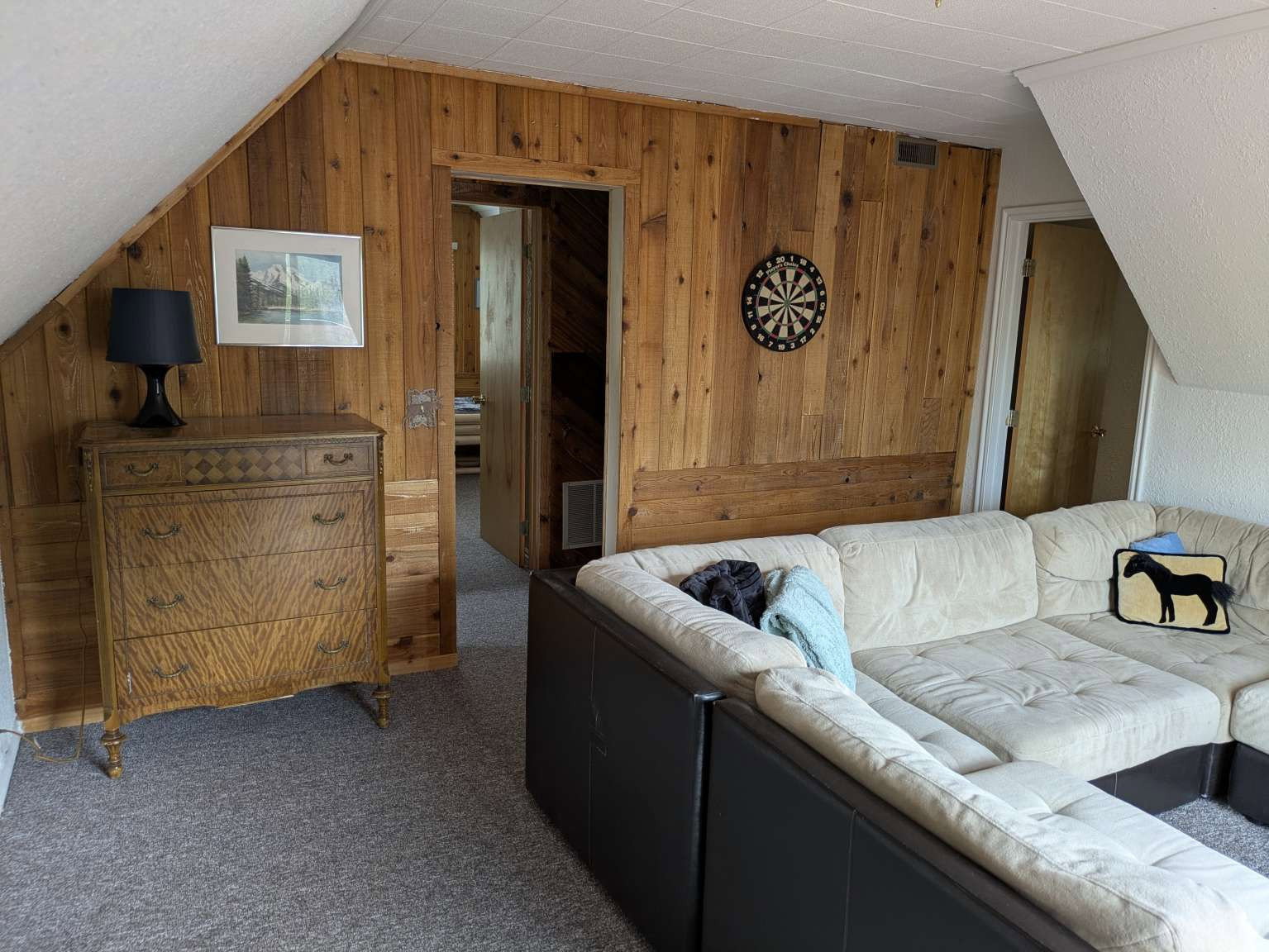 Wood-paneled wall treatments, sloped ceilings, and gray carpet flooring