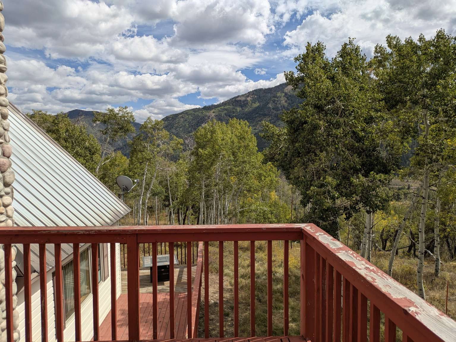 Expansive outdoor deck with red wood railing overlooking a natural landscape
