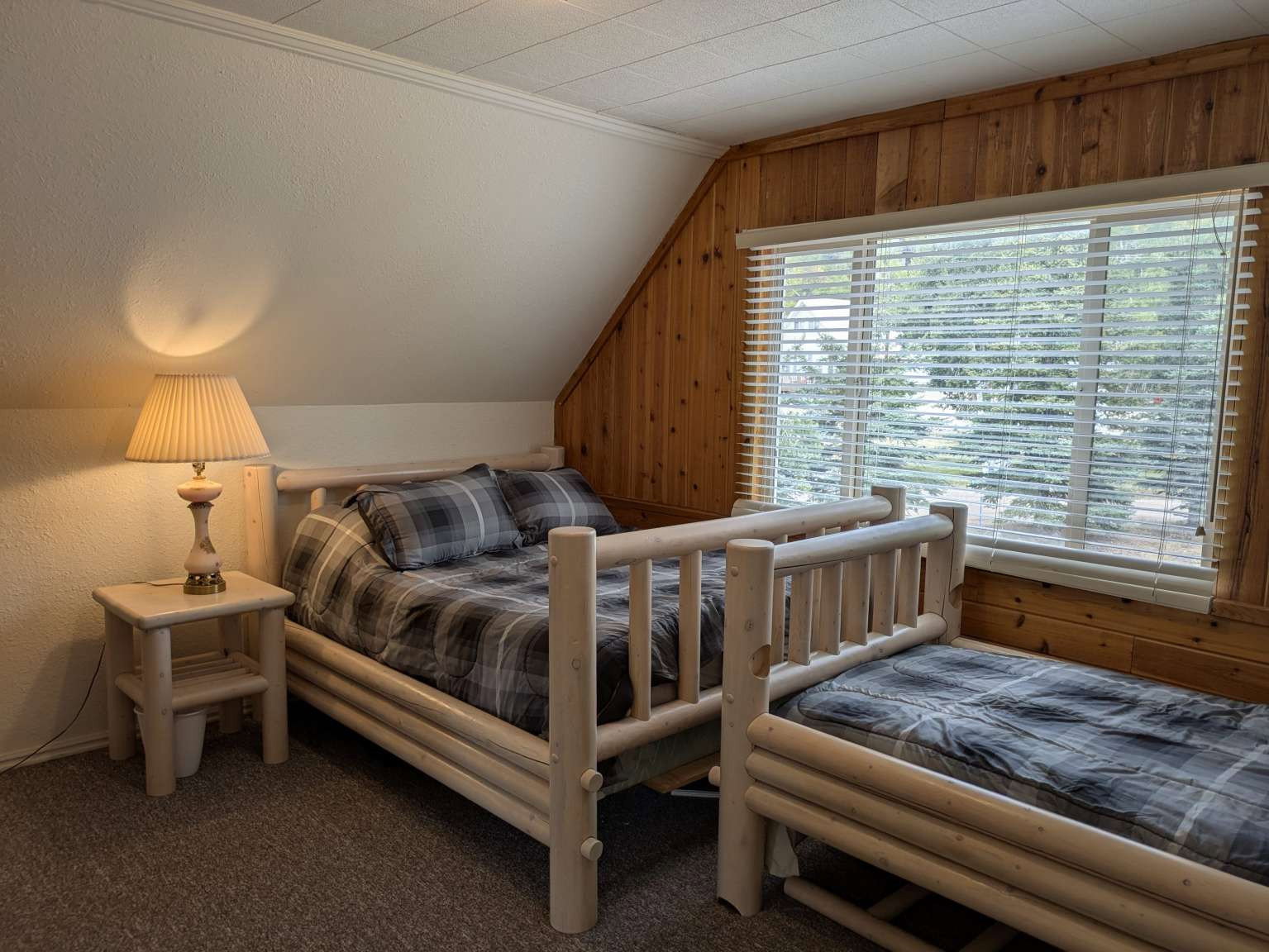 Room featuring wood-paneled accent wall, a window with horizontal blinds, and a textured ceiling