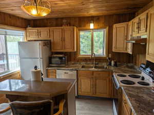Kitchen featuring wood plank walls and ceiling, light wood-finish cabinetry, speckled countertops, and a double basin stainless steel sink with a gooseneck faucet