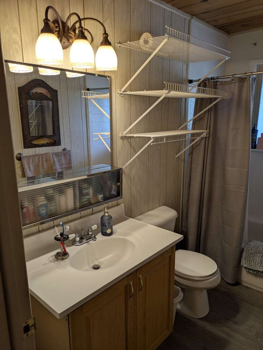 Bathroom with a wood-finish vanity, integrated sink, and wall-mounted light fixture