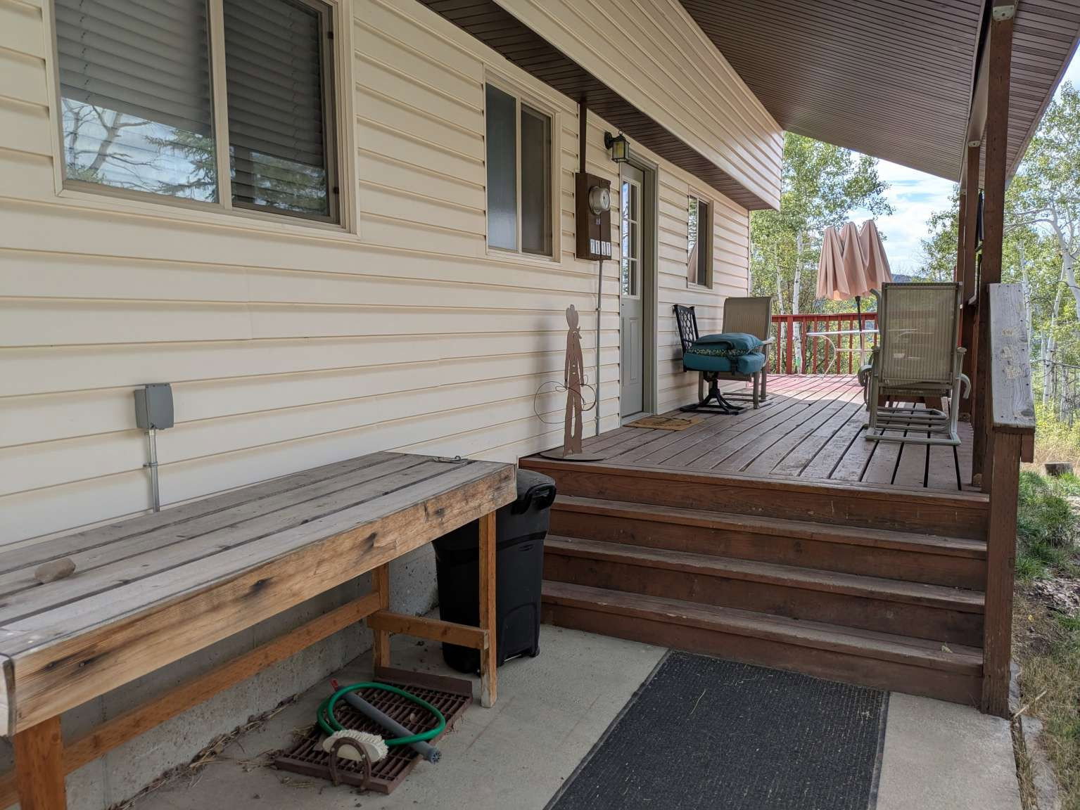Wood-finish deck with a covered area, multiple windows, and a concrete patio