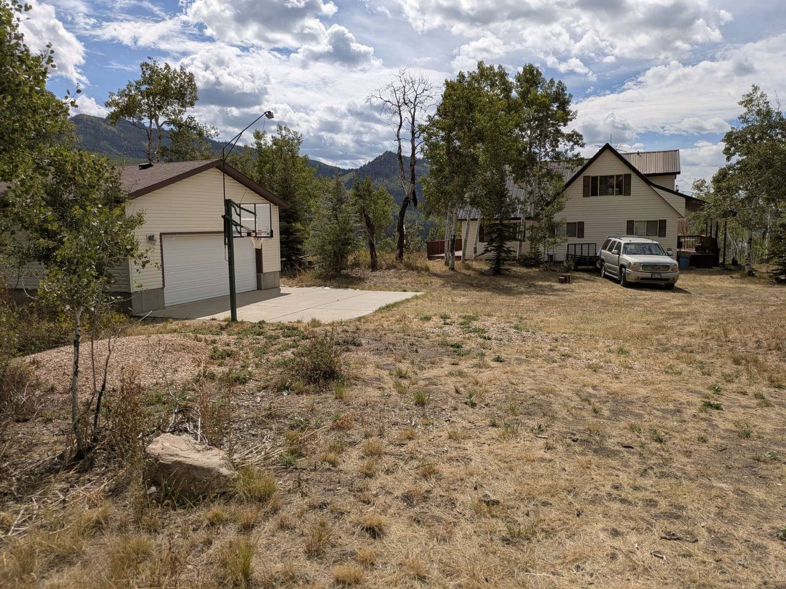 Detached garage with light-colored siding, a white garage door, and a concrete pad