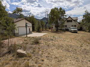 Detached garage with light-colored siding, a white garage door, and a concrete pad