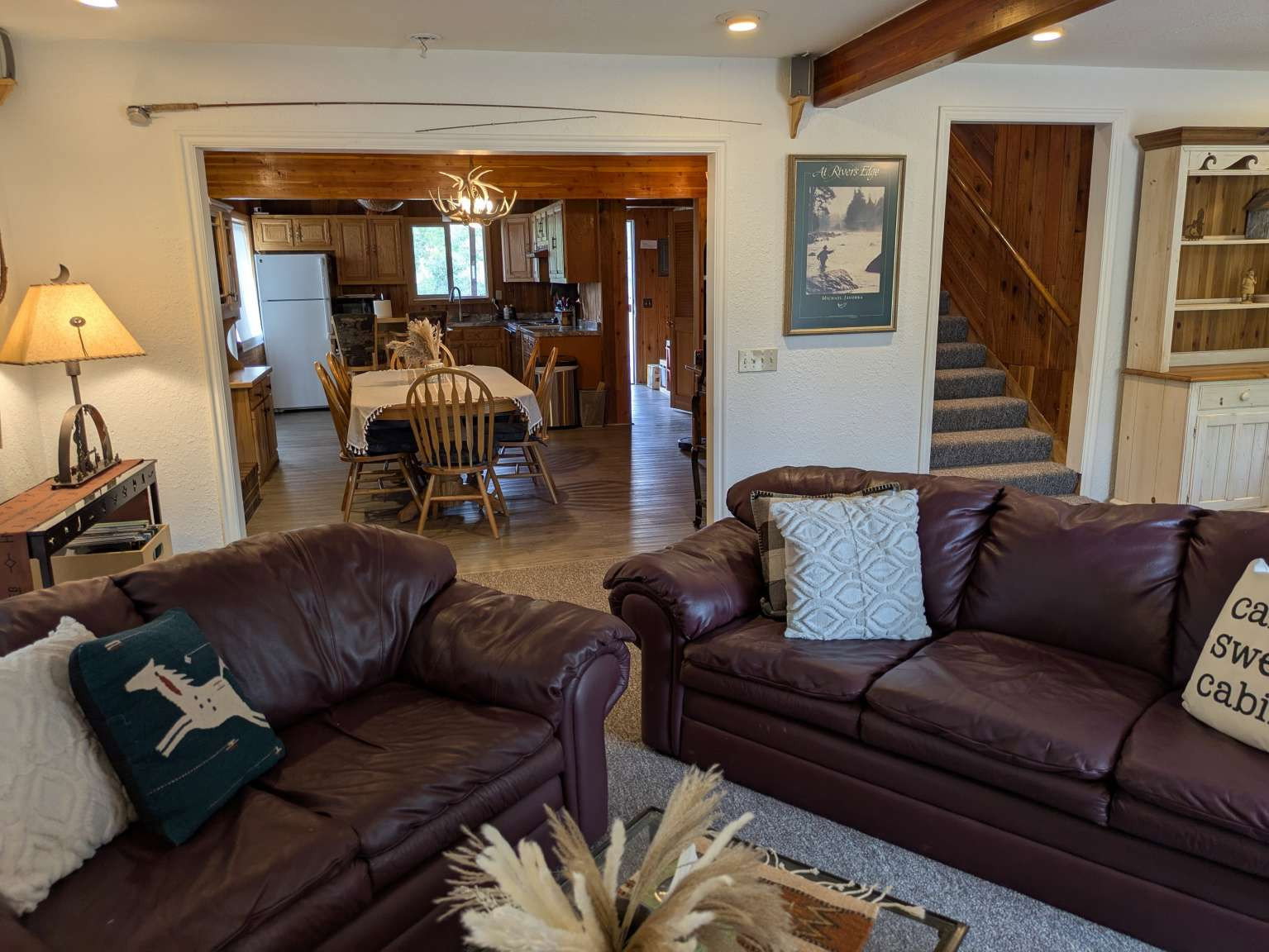 Open concept living area featuring a kitchen beyond an arched doorway, wood-finish flooring, and exposed ceiling beams