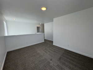 Spacious upper-level loft area with neutral carpeting and recessed lighting