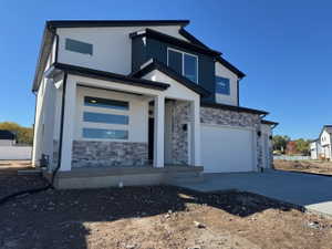 Contemporary exterior featuring white stucco, stacked stone accents, dark blue siding, black-framed windows, and a two-car garage