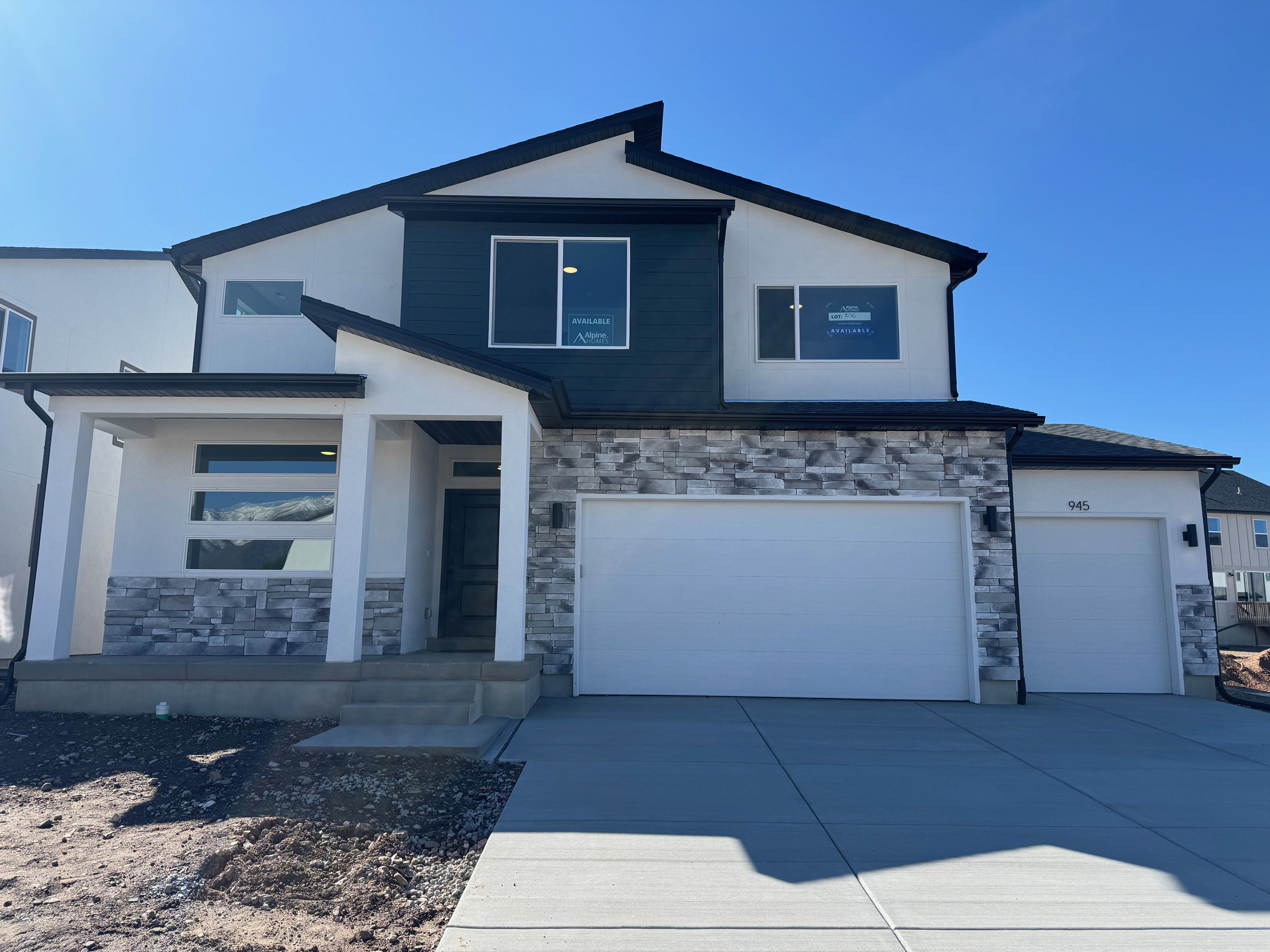 Contemporary facade featuring white stucco, dark siding, and stacked stone accents