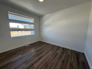 Light-filled room featuring a horizontal window design, wood-finish flooring, white baseboards, and neutral wall tones