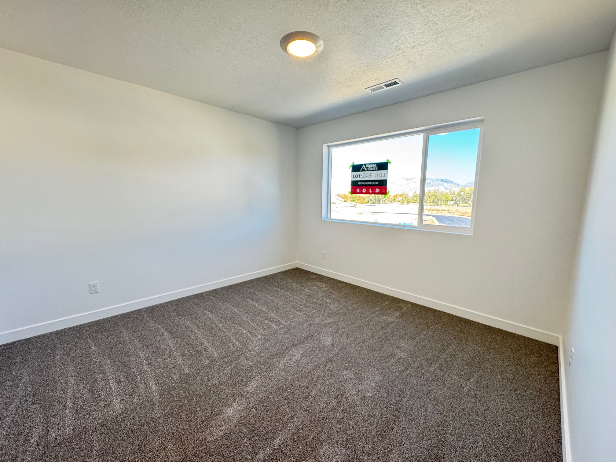 Spacious room featuring neutral carpeting, white wall paint, a large window, recessed ceiling lighting, and baseboard trim