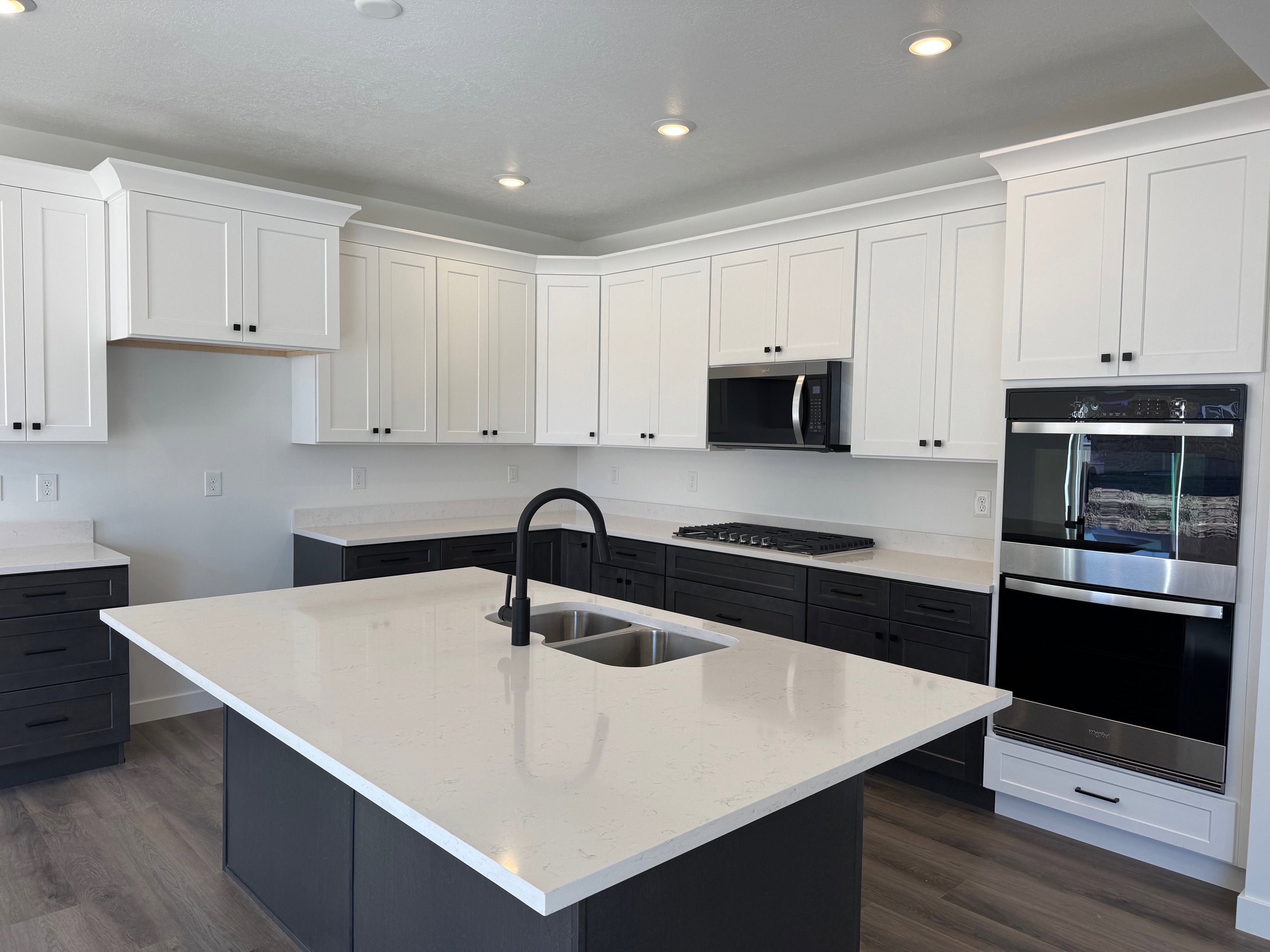 Modern kitchen featuring a large central island with a double sink and a matte black faucet