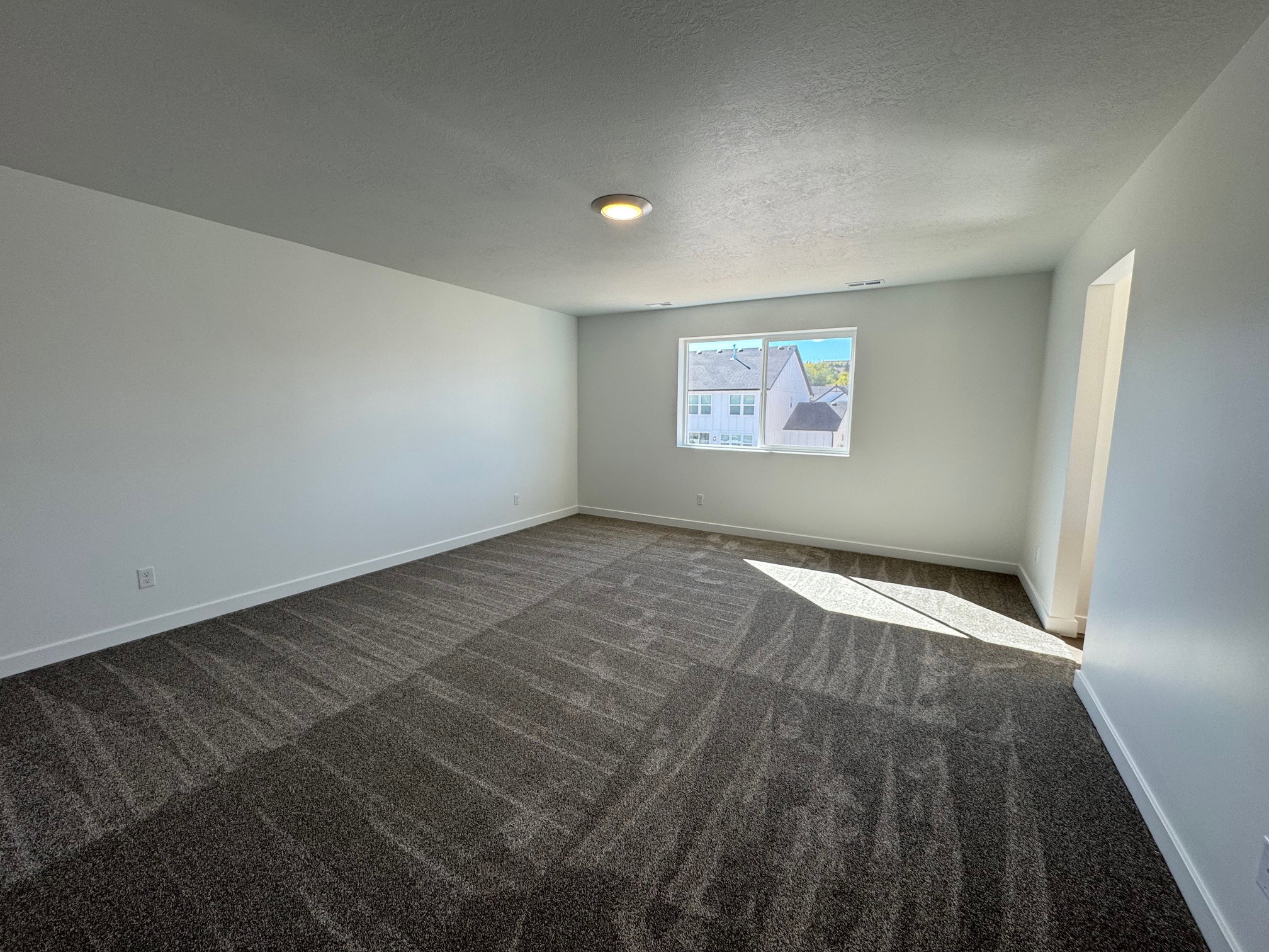 Spacious room featuring patterned carpet flooring, neutral paint palette, recessed window, and flush-mount ceiling light fixture