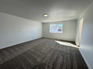 Spacious room featuring patterned carpet flooring, neutral paint palette, recessed window, and flush-mount ceiling light fixture