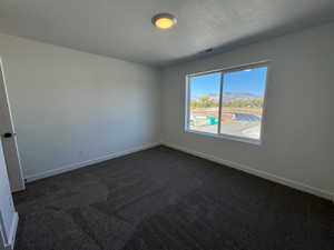 Room featuring a single window, dark gray textured carpeting, white baseboards, and a flush-mount ceiling light