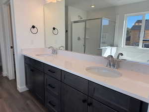 Dual sink vanity with dark wood-finish cabinetry, light-toned countertops, and chrome fixtures