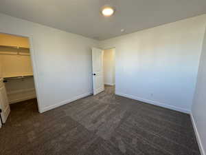 Carpeted room featuring a walk-in closet with shelving, recessed lighting, and white trim