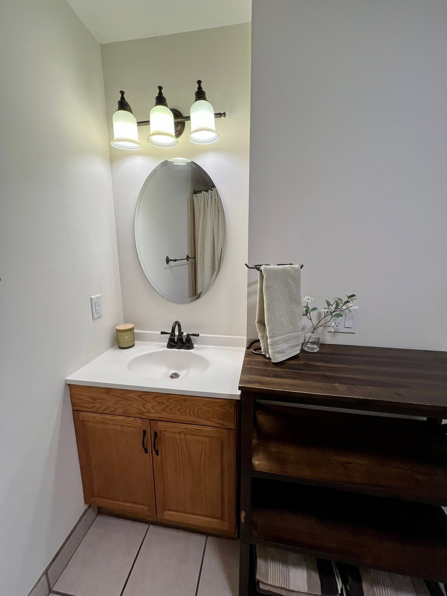 Bathroom vanity with an integrated sink, black faucet, and a three-light fixture