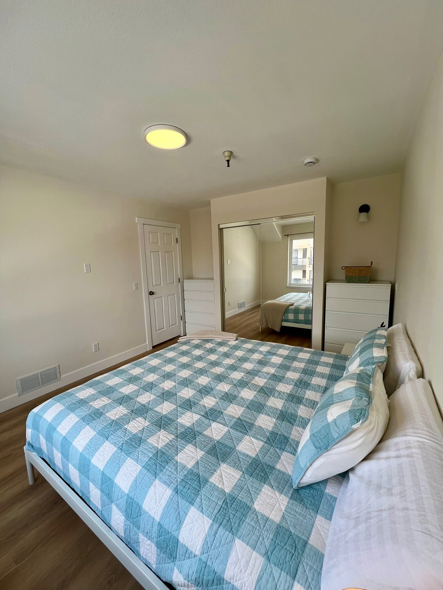 Bedroom featuring wood-finish flooring, a white panel door, and mirrored closet doors