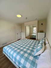 Bedroom featuring wood-finish flooring, a white panel door, and mirrored closet doors