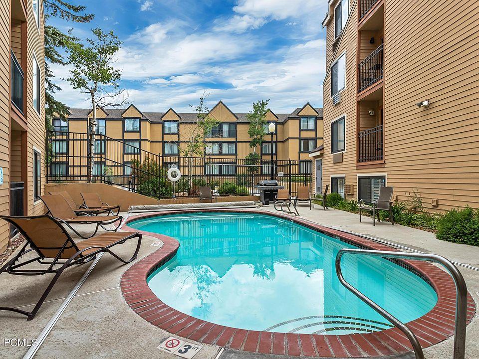 Outdoor swimming pool with brick coping, concrete pool deck, and surrounding buildings featuring balconies
