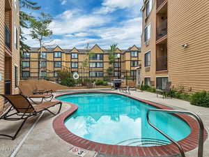 Outdoor swimming pool with brick coping, concrete pool deck, and surrounding buildings featuring balconies