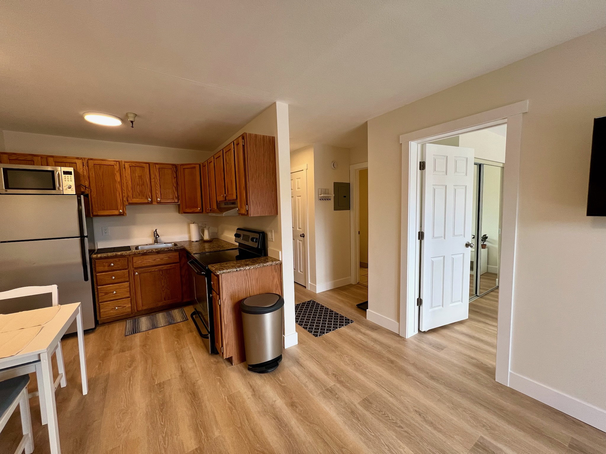 Kitchenette featuring wood-finish flooring, wood cabinetry, granite-look countertops, and stainless steel appliances
