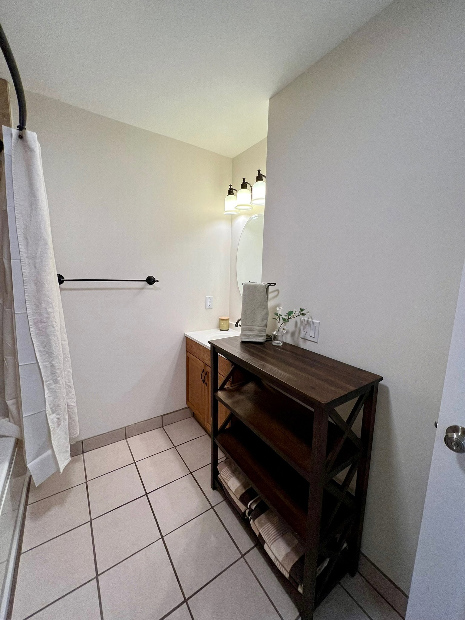 Bathroom featuring tile flooring, a wood-finish vanity with a white countertop, and a wall-mounted vanity light fixture