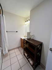 Bathroom featuring tile flooring, a wood-finish vanity with a white countertop, and a wall-mounted vanity light fixture