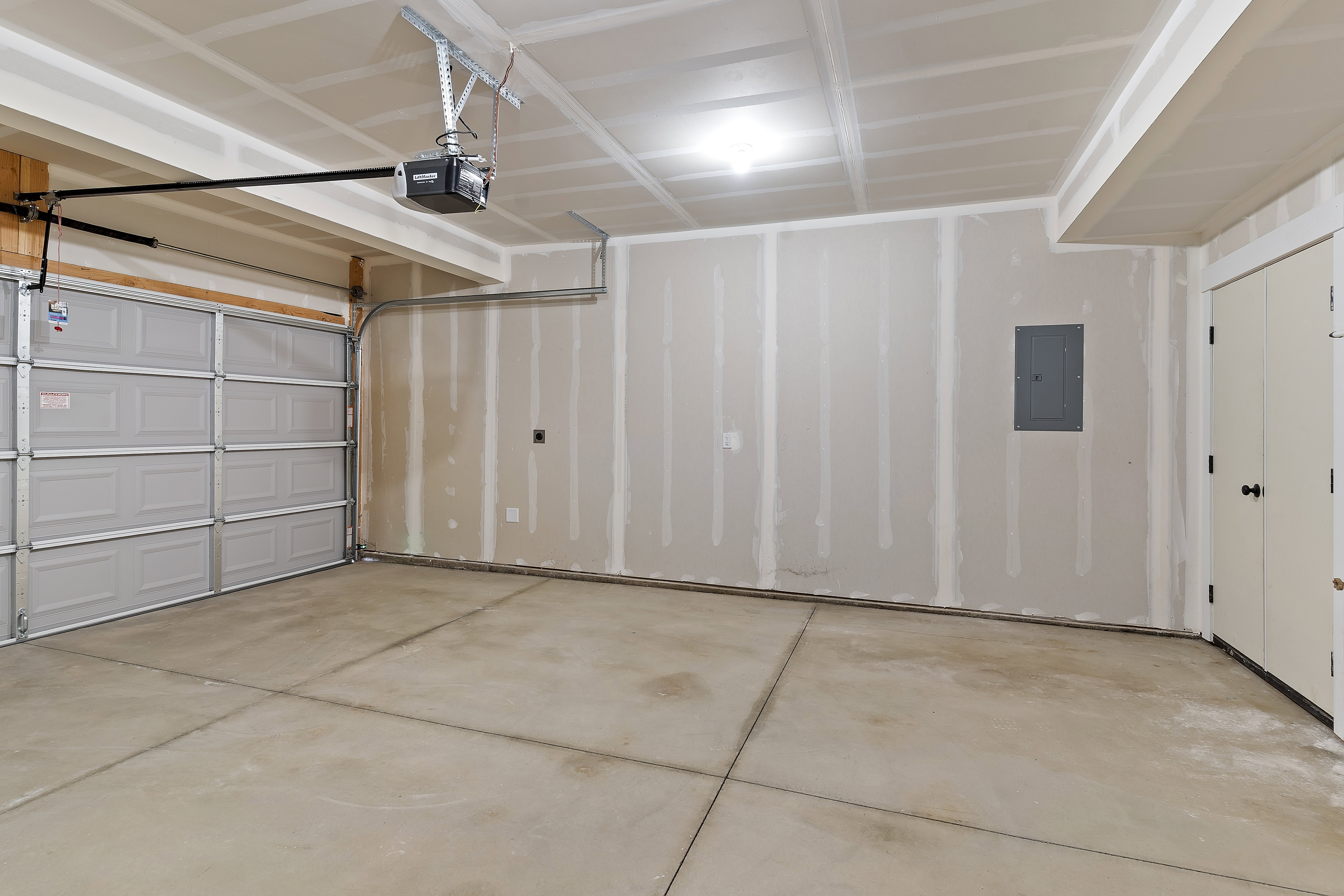 Spacious garage with an overhead automatic door opener, concrete flooring, and a flush-mounted ceiling light