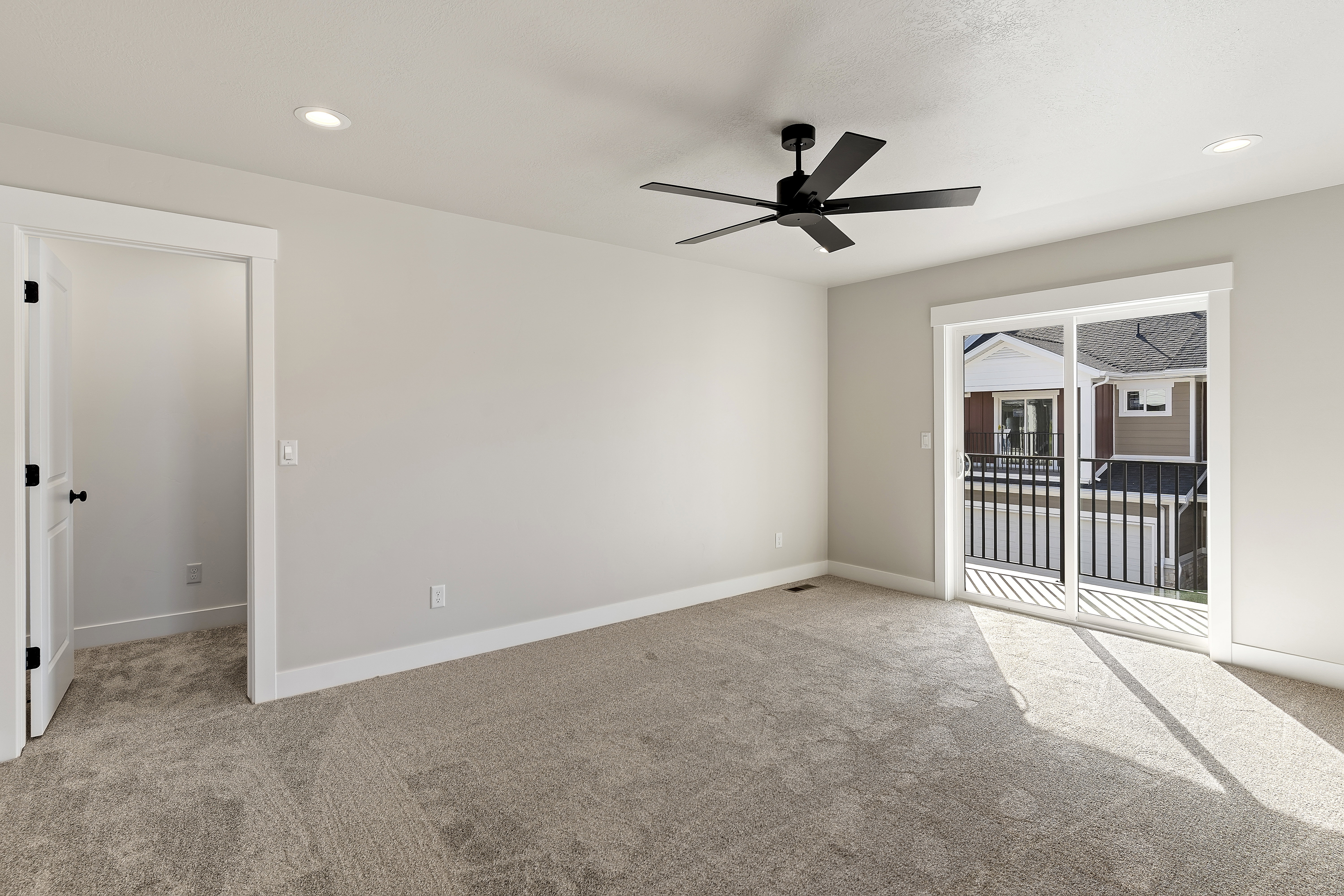 Carpeted room with a sliding glass door opening to an exterior balcony featuring black metal railings