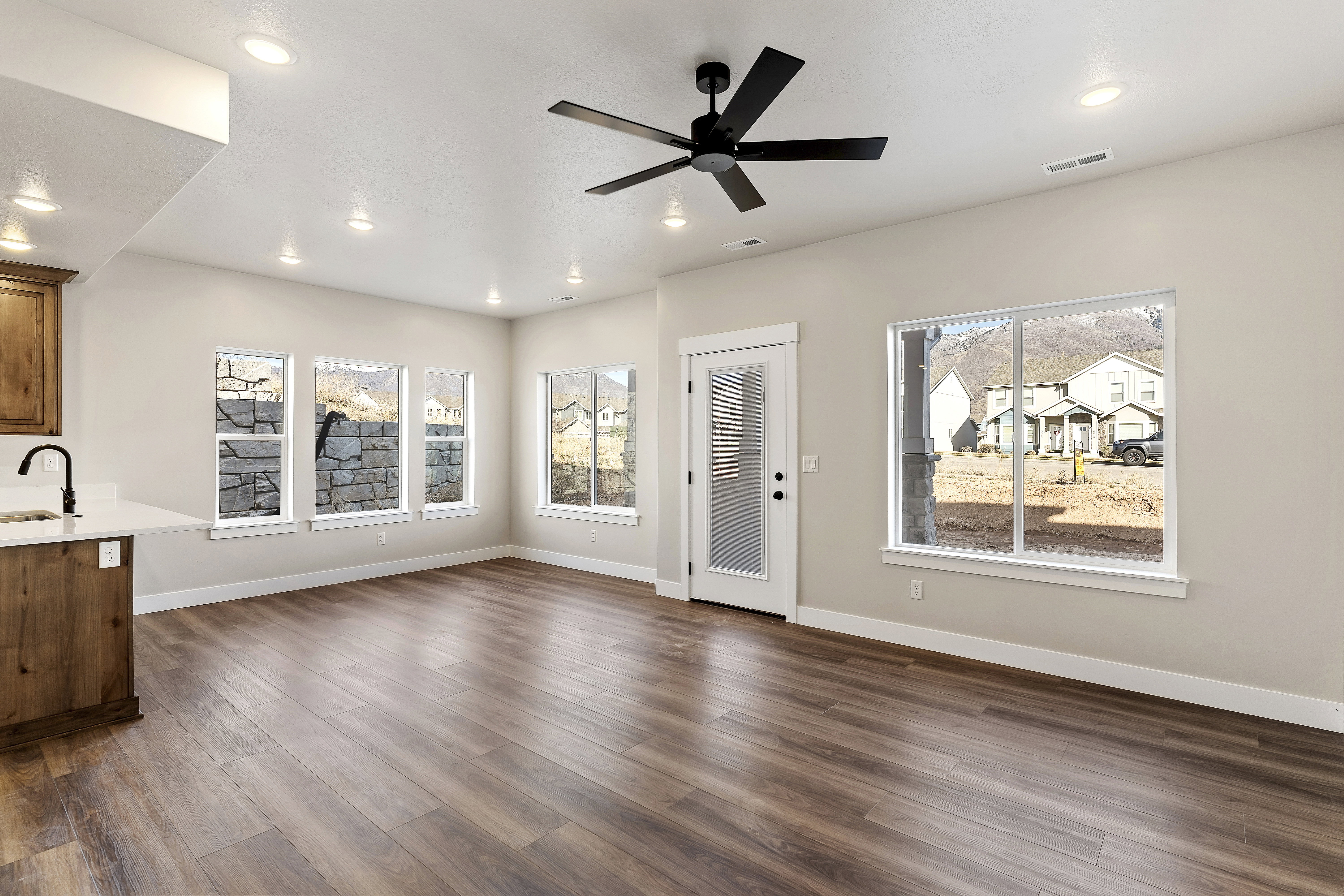 Spacious room featuring wood-finish flooring, recessed lighting, and a contemporary ceiling fan