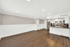 Expansive open-concept living area featuring wood-finish flooring, wainscoting, and recessed lighting