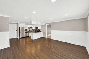Open-concept living area featuring wood-finish flooring, recessed lighting, and wainscoting