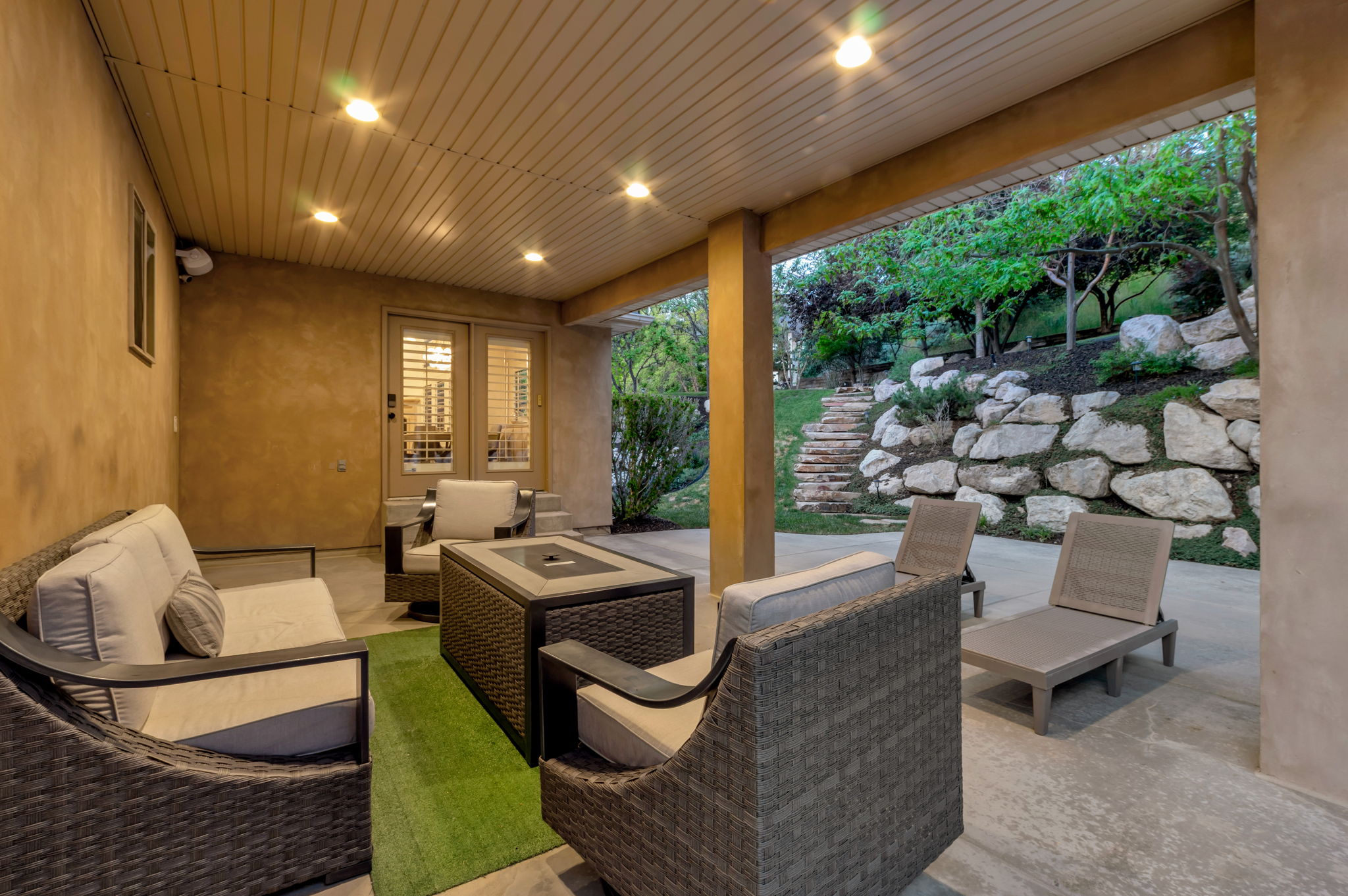 Covered outdoor living area with recessed lighting, generous entertaining space, and a seamless connection to the beautifully landscaped backyard.
