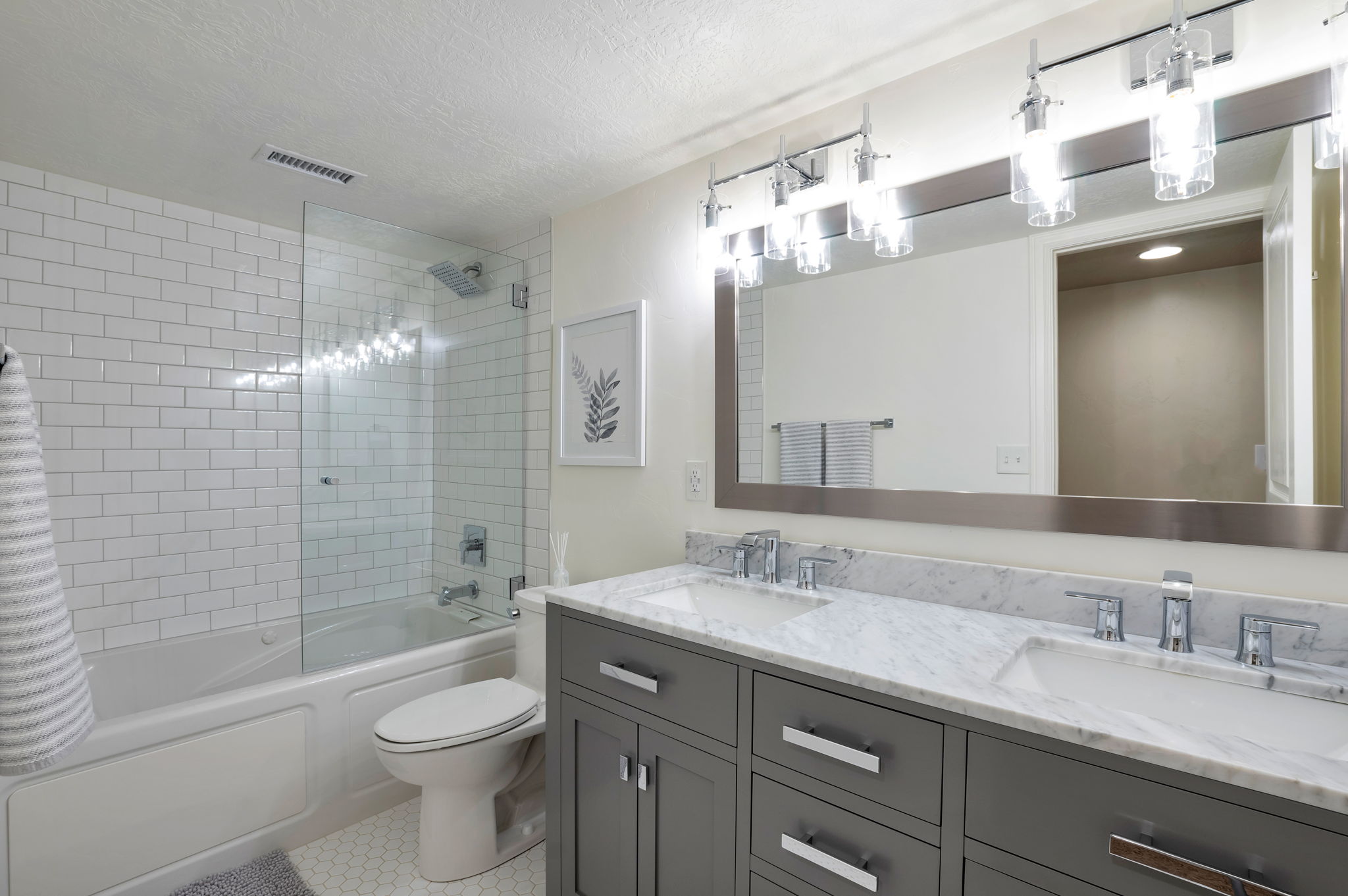 Spacious bathroom featuring a dual vanity and beautifully tiled tub/shower combination.