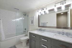 Bathroom featuring a dual vanity with a light-toned countertop, modern chrome fixtures, a frameless mirror, and contemporary lighting