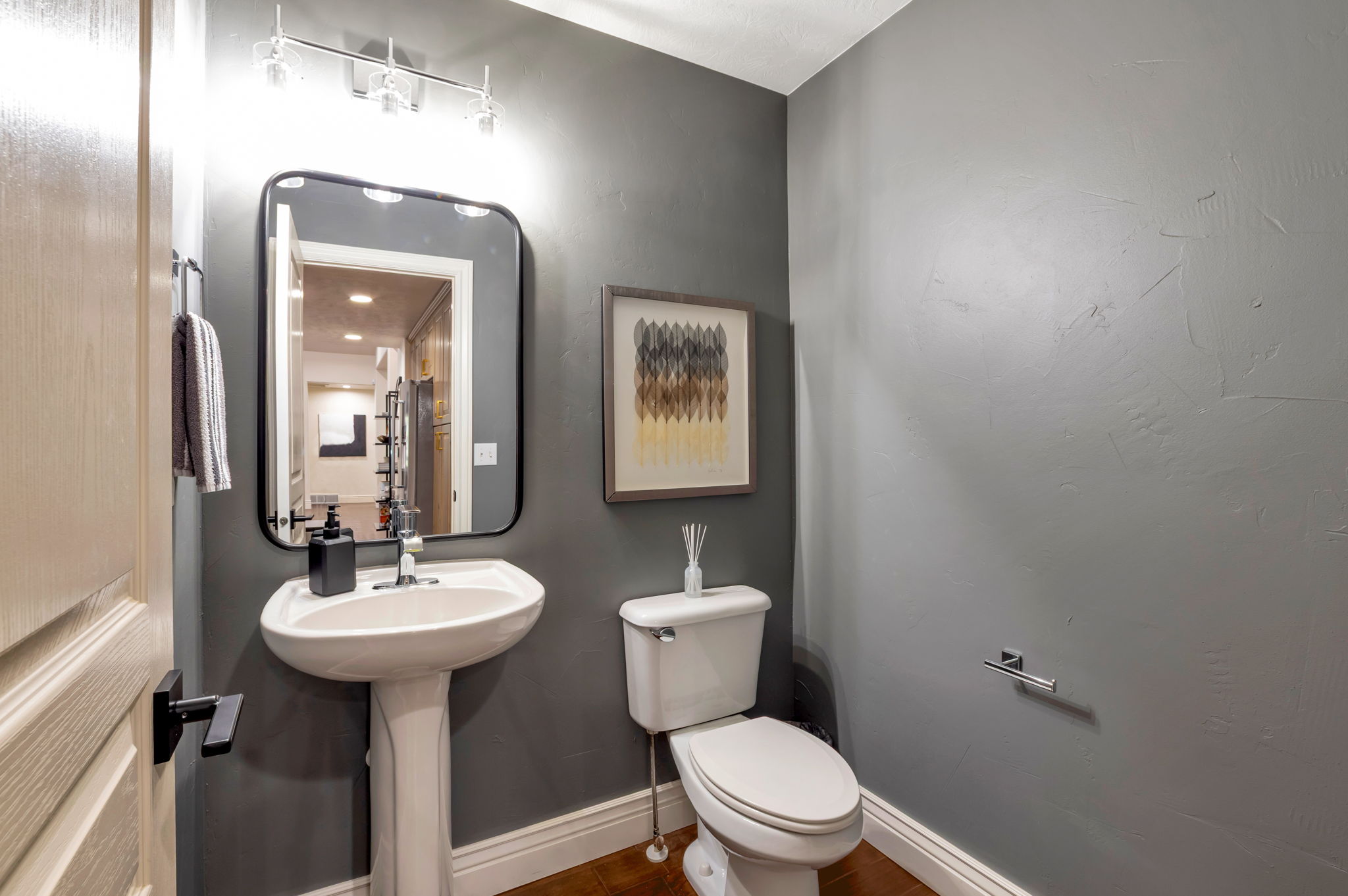 Convenient main-level powder room for guests, featuring a pedestal sink and a wall-mounted mirror.