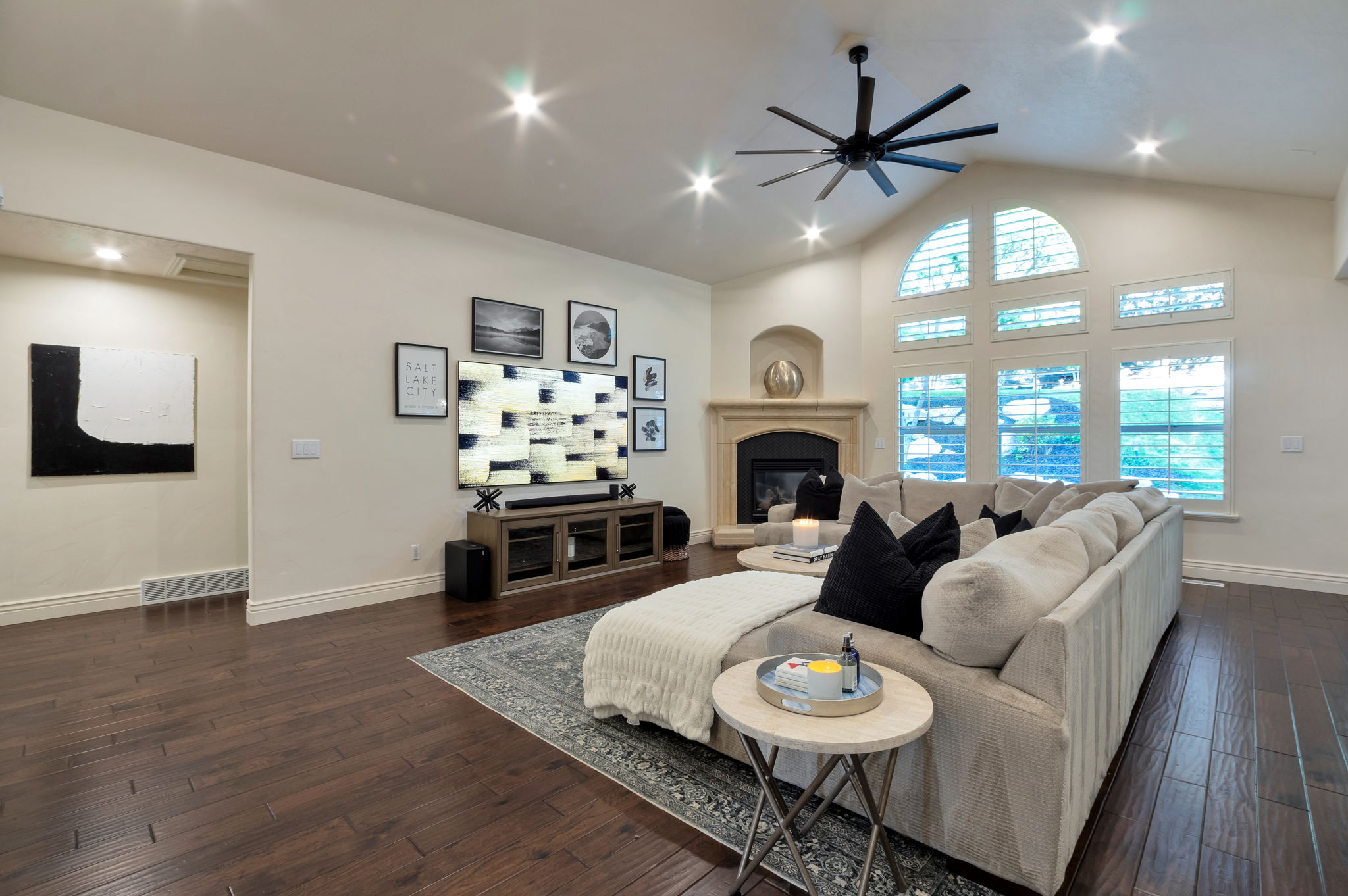 Dramatic great room featuring vaulted ceilings, oversized windows, stone fireplace, and abundant natural light.