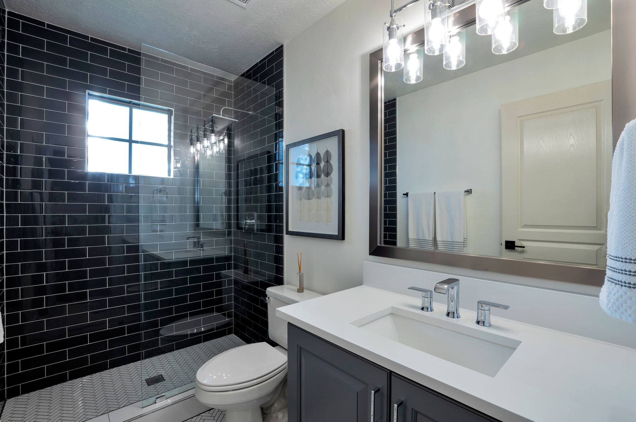 Updated secondary bathroom with custom tile, frameless glass shower, and modern finishes.