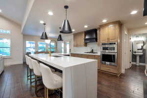 Gourmet kitchen featuring a waterfall island with integrated sink, gold-finish faucet, and pendant lighting