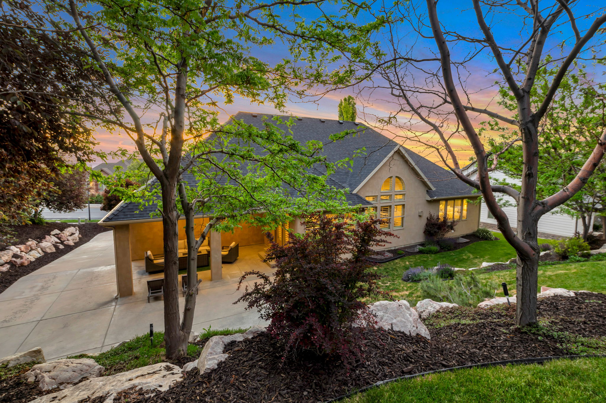 Private backyard retreat featuring mature trees, custom rockscaping, and a covered patio designed for year-round outdoor living.